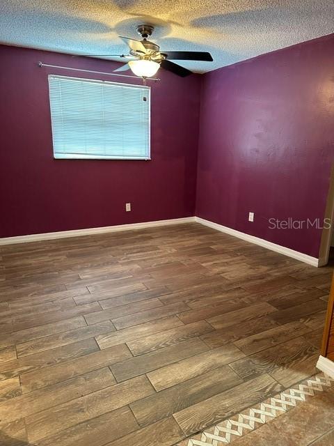 empty room featuring ceiling fan, hardwood / wood-style flooring, and a textured ceiling