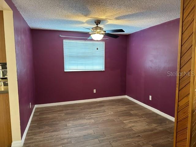 empty room featuring a textured ceiling, ceiling fan, and dark hardwood / wood-style floors