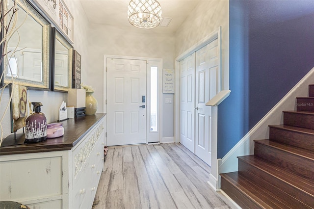 foyer entrance with wood-type flooring and a chandelier