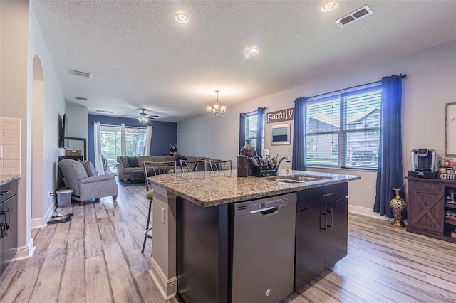 kitchen featuring ceiling fan with notable chandelier, a center island with sink, dishwasher, light hardwood / wood-style flooring, and sink