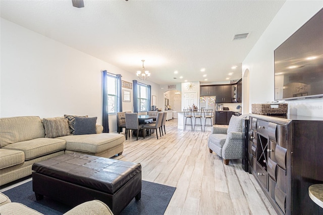 living room with light hardwood / wood-style floors, a notable chandelier, and a textured ceiling