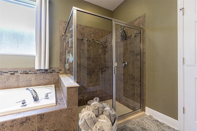 bathroom with a textured ceiling and separate shower and tub