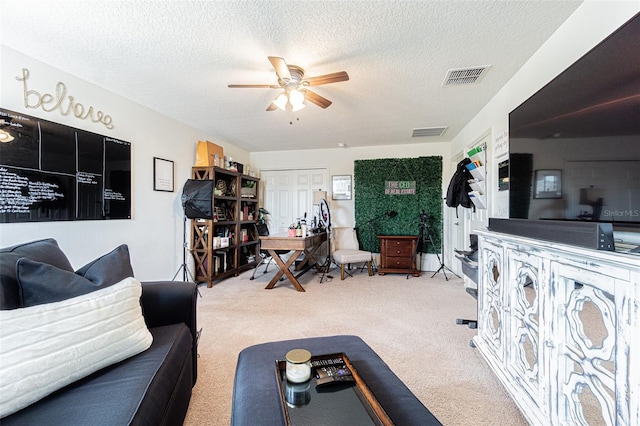 carpeted living room featuring ceiling fan and a textured ceiling