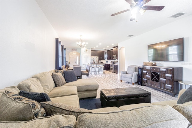 living room with light wood-type flooring and ceiling fan with notable chandelier