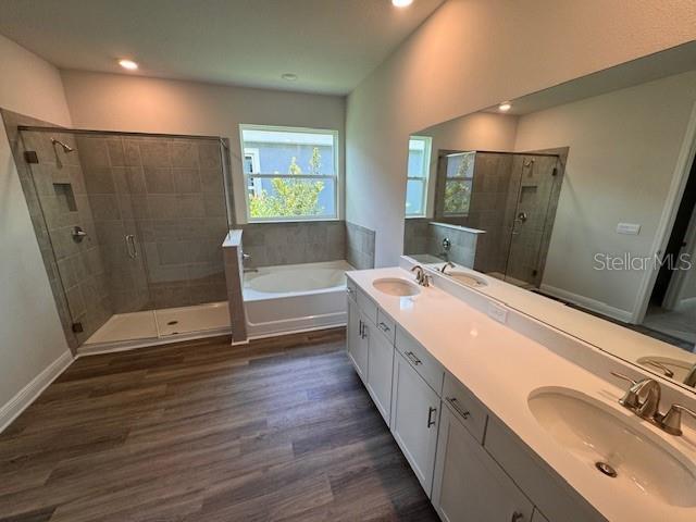 4303 Pullet Ct, Lakewood Ranch, FL 34211 - full bath featuring a garden tub, a stall shower, wood finished floors, double vanity, and recessed lighting
