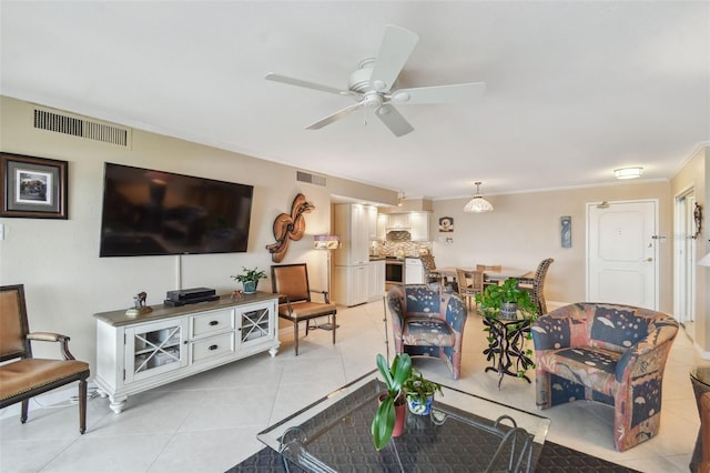 living room with a ceiling fan, visible vents, ornamental molding, and light tile patterned floors