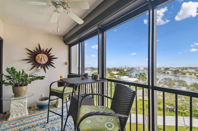 sunroom featuring a water view and ceiling fan