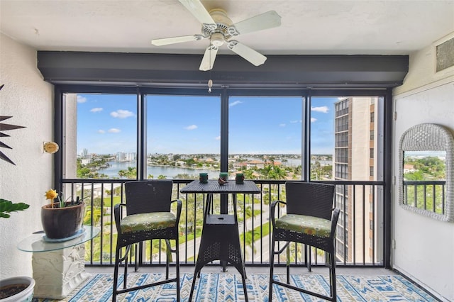 sunroom featuring a water view and ceiling fan