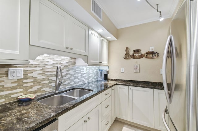 kitchen featuring sink, white cabinets, stainless steel refrigerator, crown molding, and dark stone countertops