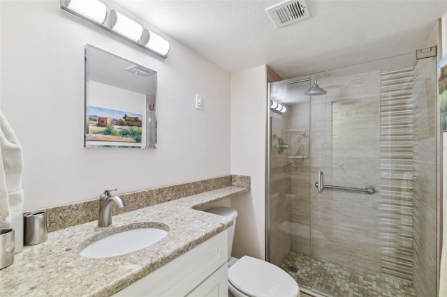 bathroom with vanity, toilet, a textured ceiling, a shower stall, and visible vents