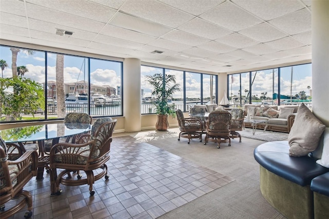 sunroom / solarium with a drop ceiling, a wealth of natural light, and a water view