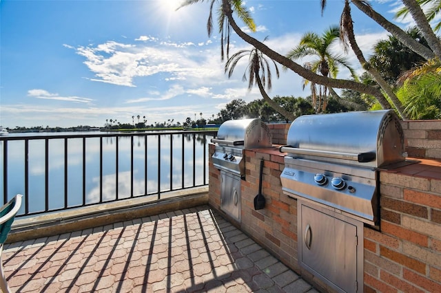 view of patio / terrace with a water view, an outdoor kitchen, and a grill