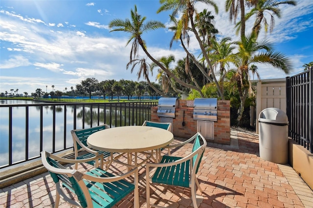 view of patio with a water view, area for grilling, and an outdoor kitchen