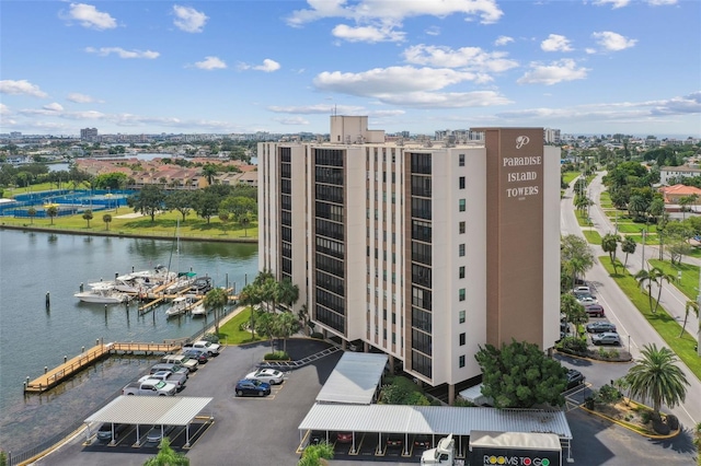 view of building exterior featuring a water view, uncovered parking, and a city view