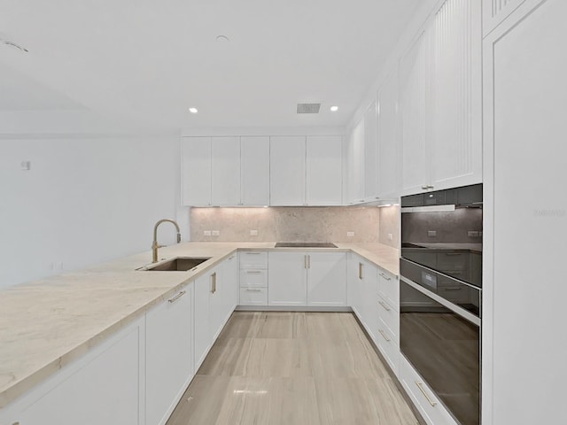 kitchen featuring decorative backsplash, light hardwood / wood-style floors, sink, and white cabinets