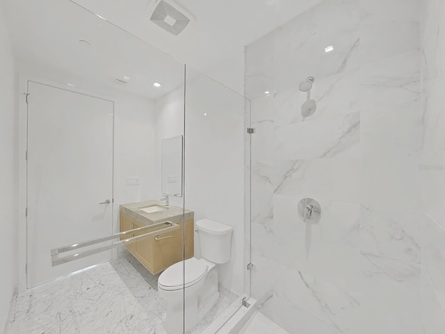 bathroom with tiled shower, vanity, and toilet