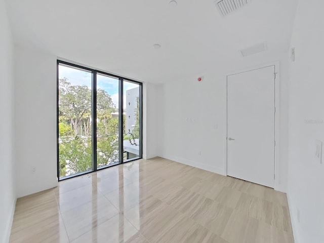 spare room with a wall of windows and plenty of natural light