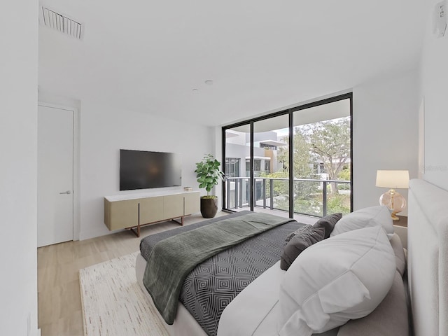 bedroom featuring light wood-type flooring, a wall of windows, and access to outside