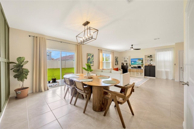 tiled dining area with ceiling fan with notable chandelier