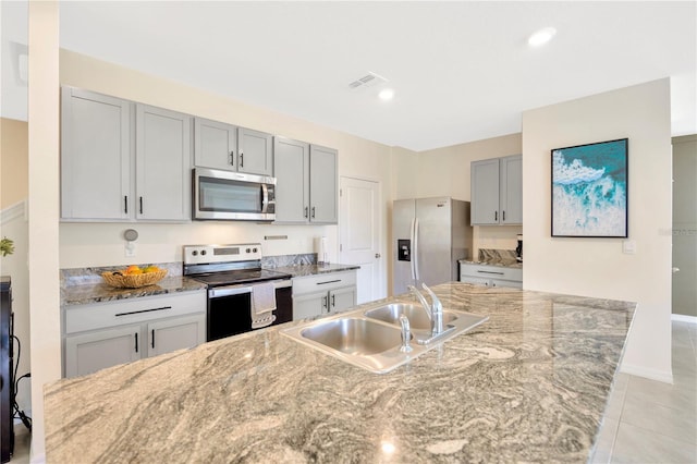 kitchen featuring gray cabinetry, appliances with stainless steel finishes, light stone countertops, sink, and light tile patterned flooring