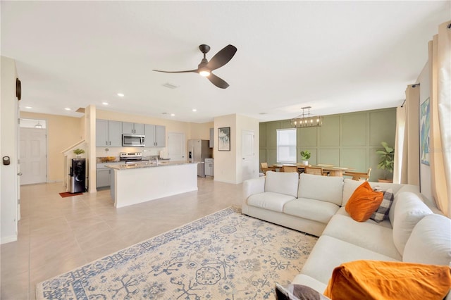 tiled living room featuring ceiling fan with notable chandelier