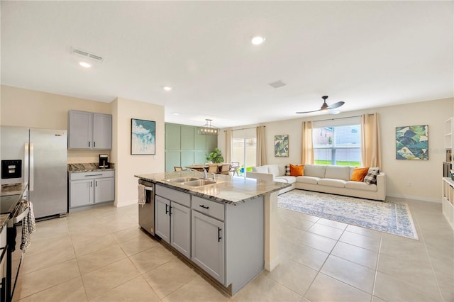 kitchen with light tile patterned floors, an island with sink, stainless steel appliances, gray cabinets, and ceiling fan