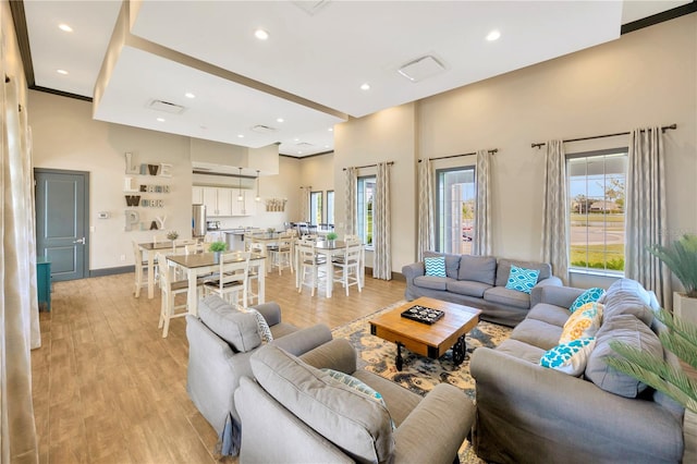 living room with a towering ceiling and light hardwood / wood-style floors