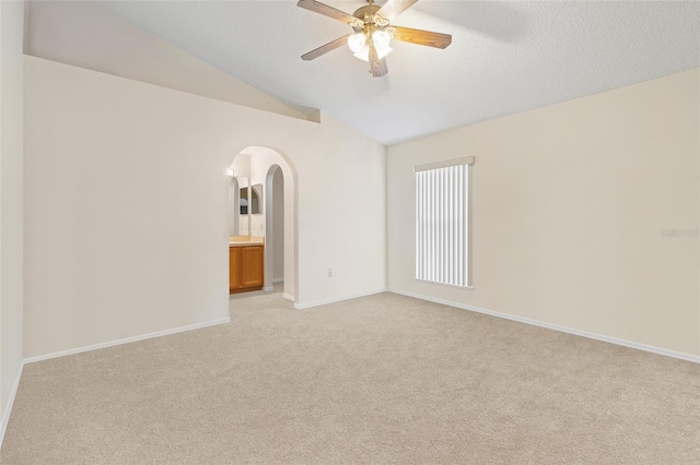 carpeted spare room with a textured ceiling, lofted ceiling, and ceiling fan