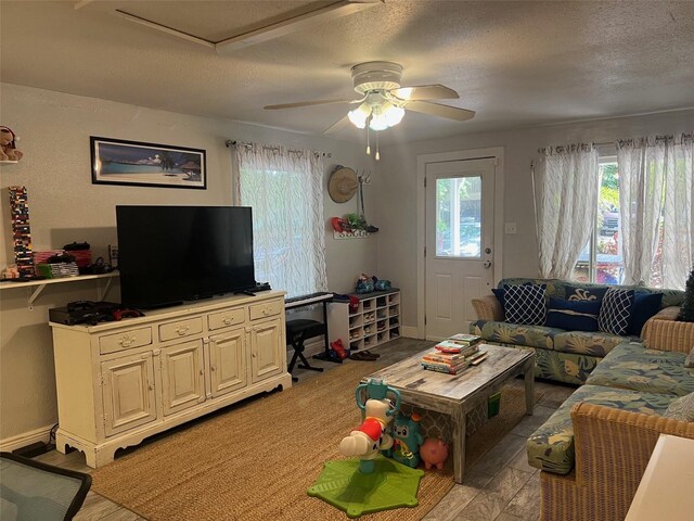 living room featuring a textured ceiling, ceiling fan, and light hardwood / wood-style flooring