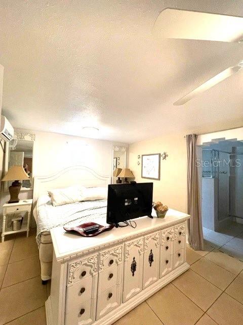 bedroom featuring a textured ceiling, an AC wall unit, and light tile patterned floors