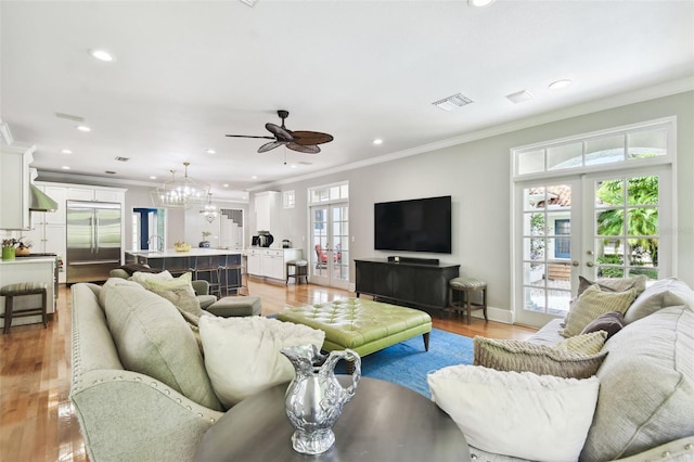 living room with plenty of natural light, ceiling fan with notable chandelier, french doors, and light hardwood / wood-style floors