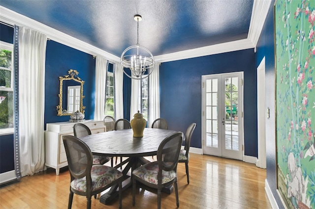 dining room featuring a wealth of natural light, ornamental molding, french doors, and light hardwood / wood-style floors