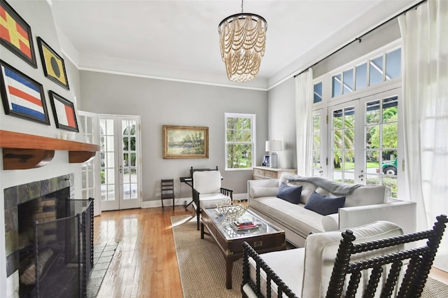 living room with a wealth of natural light, a notable chandelier, french doors, and light hardwood / wood-style floors