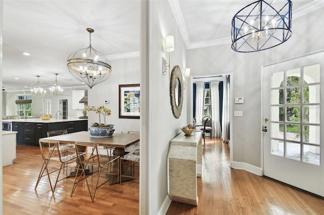 dining space featuring crown molding, an inviting chandelier, sink, and light hardwood / wood-style floors