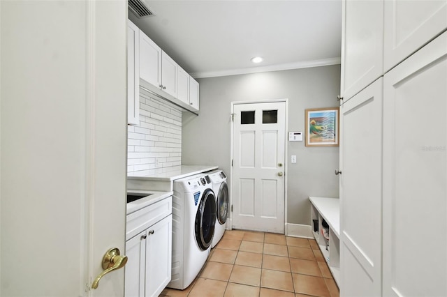 clothes washing area with crown molding, cabinets, washing machine and dryer, and light tile patterned flooring