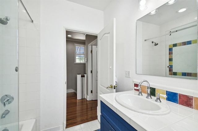 bathroom featuring hardwood / wood-style floors, tiled shower / bath, backsplash, and vanity