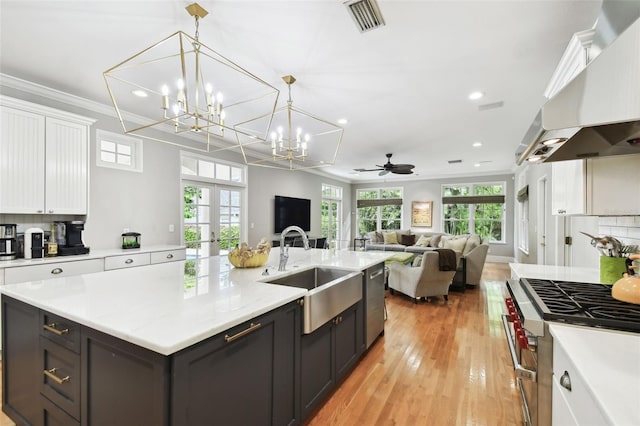 kitchen with ceiling fan with notable chandelier, light hardwood / wood-style flooring, sink, appliances with stainless steel finishes, and white cabinets