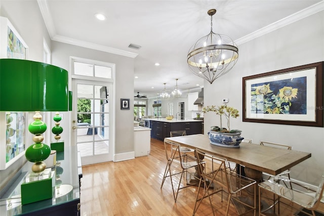 dining space with crown molding, light hardwood / wood-style flooring, and an inviting chandelier