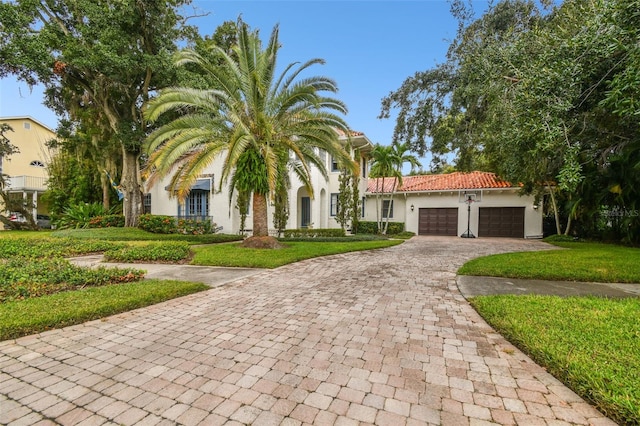 mediterranean / spanish home featuring a garage and a front lawn