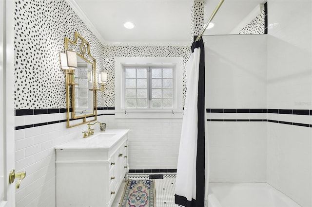 bathroom featuring tile walls, shower / bath combo with shower curtain, ornamental molding, and vanity