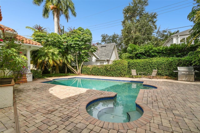 view of pool with grilling area and a patio