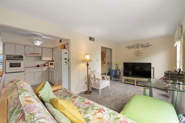 carpeted living room with ceiling fan