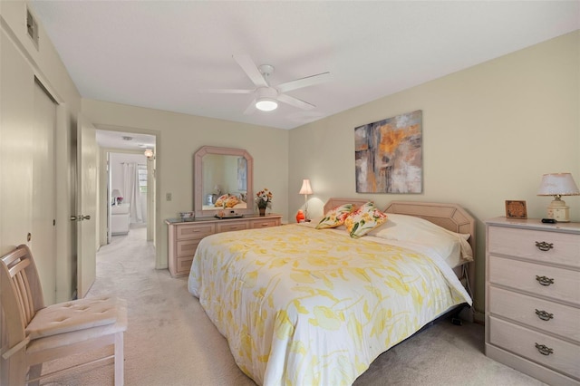 bedroom featuring light colored carpet, ceiling fan, and a closet