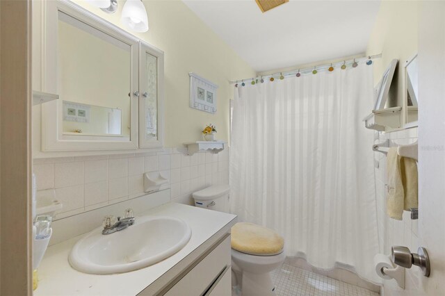 bathroom with toilet, tile patterned floors, vanity, tile walls, and a shower with shower curtain