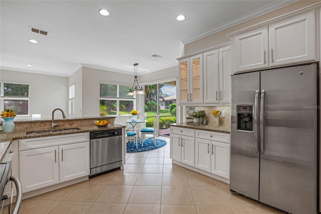 kitchen with stainless steel appliances, sink, white cabinetry, and dark stone counters