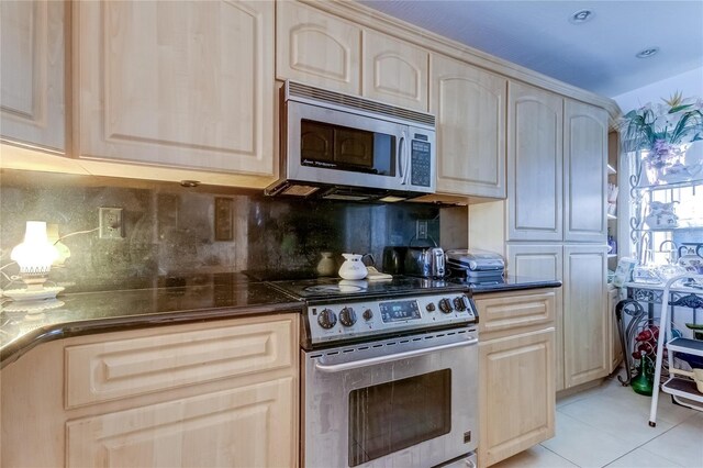 kitchen featuring appliances with stainless steel finishes, light brown cabinets, and decorative backsplash