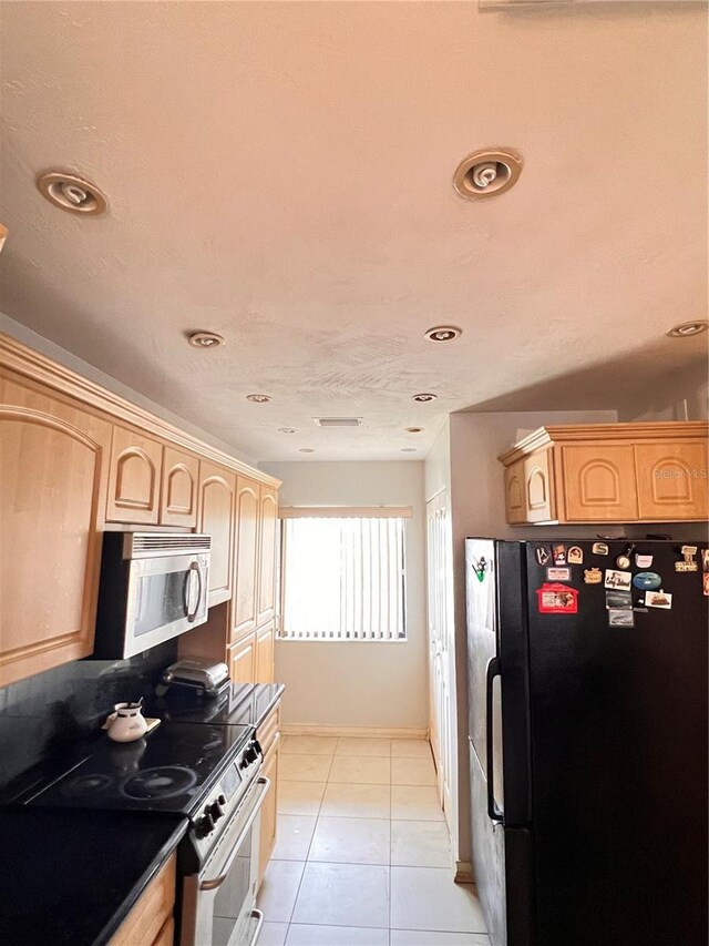 kitchen with light tile patterned floors, stainless steel appliances, and light brown cabinets