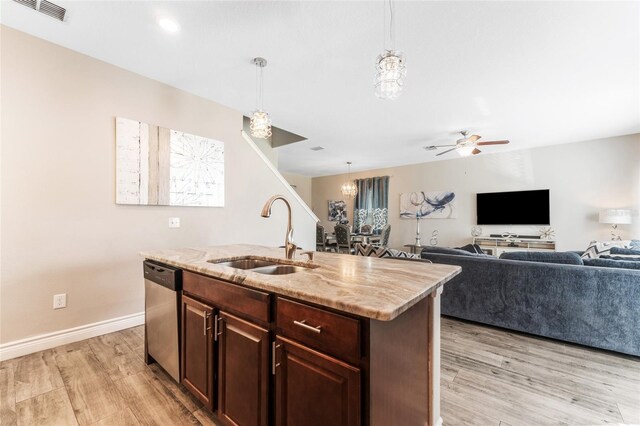 kitchen featuring an island with sink, sink, stainless steel dishwasher, ceiling fan with notable chandelier, and light hardwood / wood-style floors