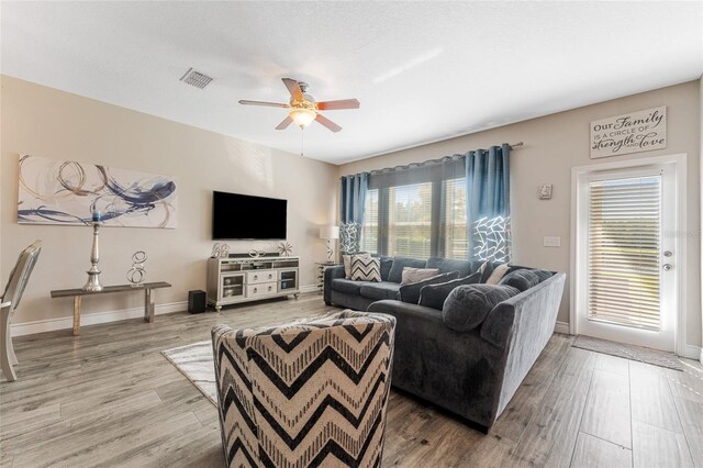 living area with a wealth of natural light, visible vents, and wood finished floors