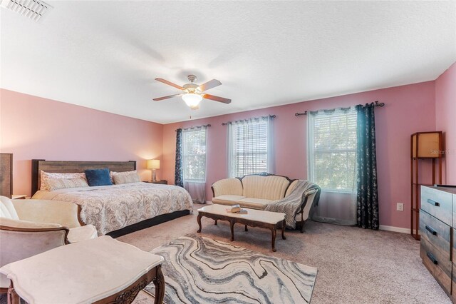 carpeted bedroom featuring ceiling fan and a textured ceiling